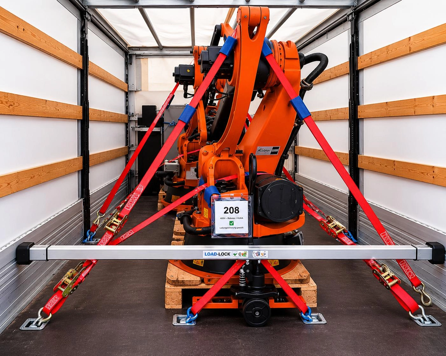 RK-TRANSPORTE – Transport- und Logistikdienstleistungen – Oranger Industrieroboterarm, der mit roten Gurten in einem Lieferwagen gesichert ist.